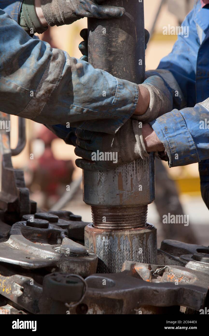 Bohrgeräteingenieure bauen neue Rohre an einem Explorationsbohrloch an, das Teil eines Brunnennetzes ist, das eine neue Ölanlage in der Wüste Sahara speist. Stockfoto