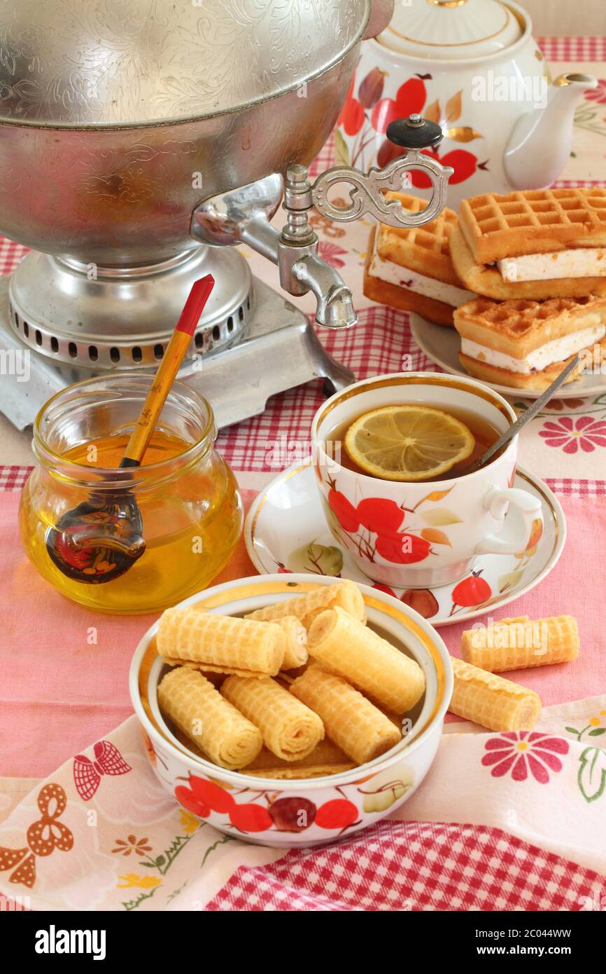 Tee aus einem Samowar, mit einer Zitrone, Honig, Kuchen und Waffeln Stockfoto