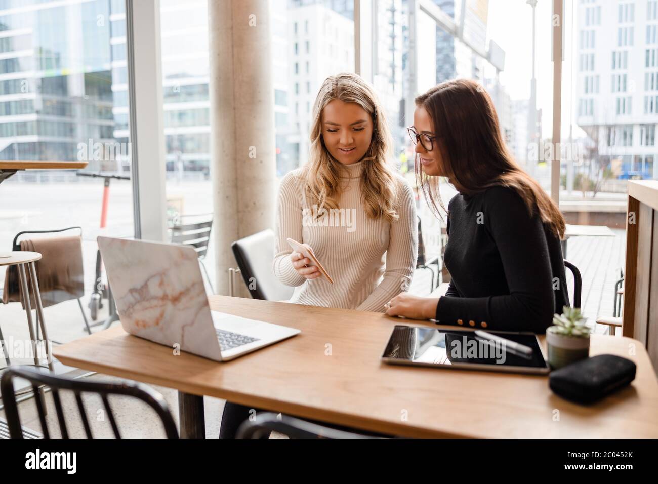 Schöne Blogger Geselligkeit auf Smartphone und Laptop im Café Stockfoto