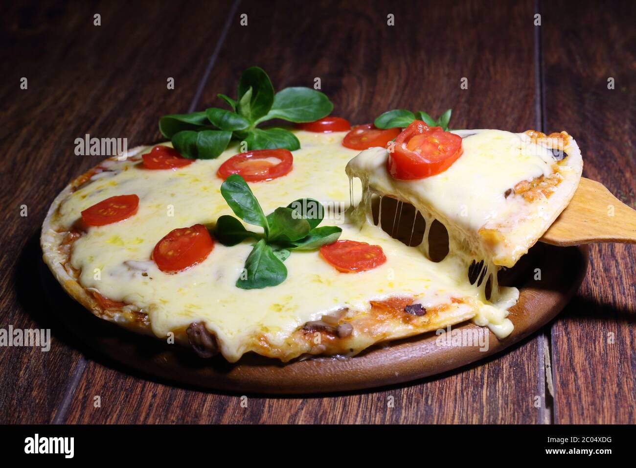 Stück Pizza mit dem Schmelzkäse auf der hölzernen Schaufel Stockfoto