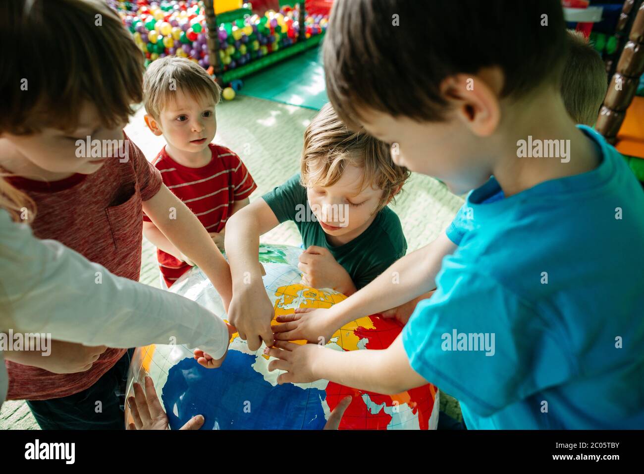 Kinder lernen mit einem aufblasbaren Kugelball über Länder Stockfoto