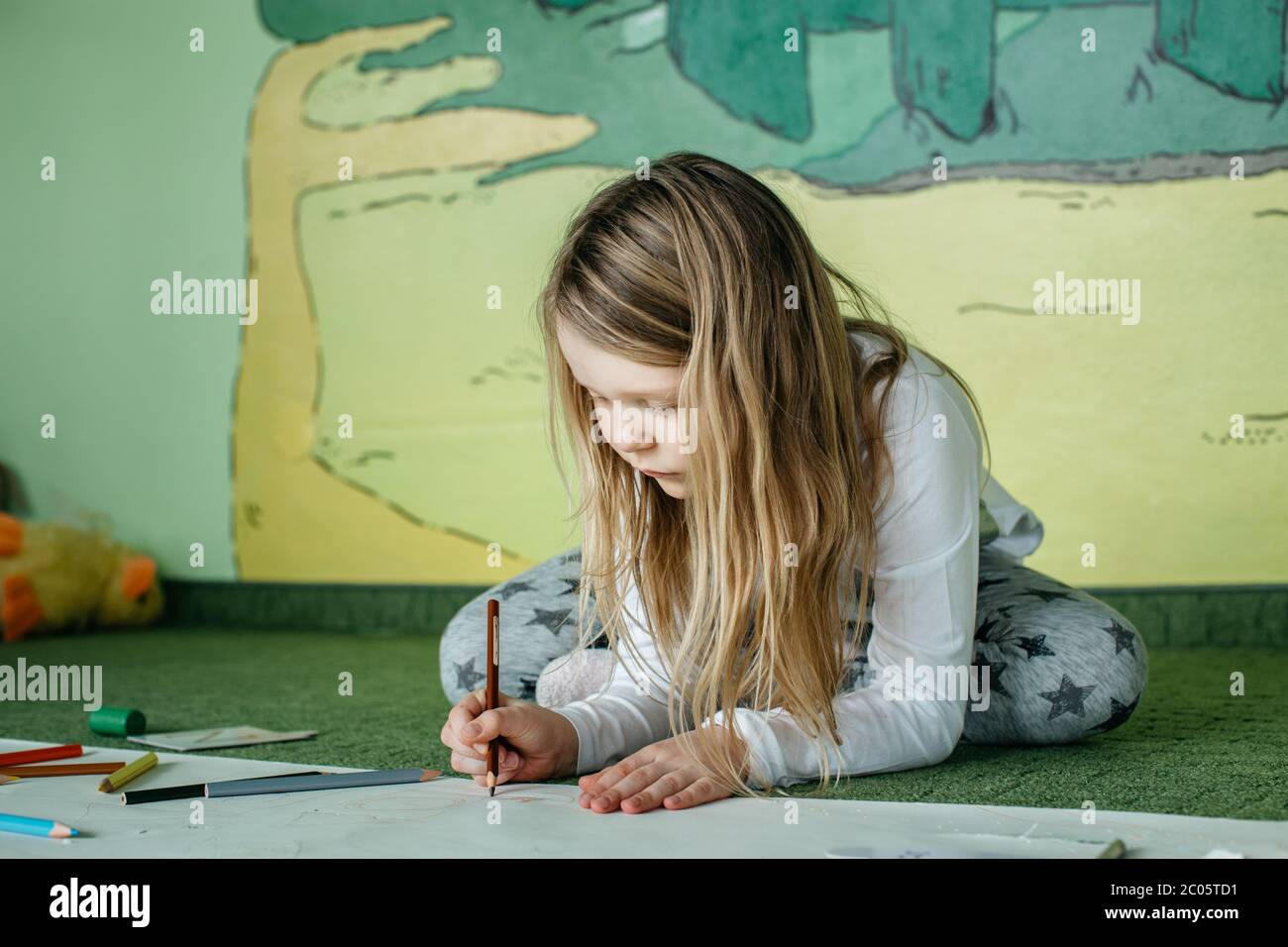 Mädchen auf dem Boden sitzen und ein Bild mit Buntstiften zeichnen Stockfoto