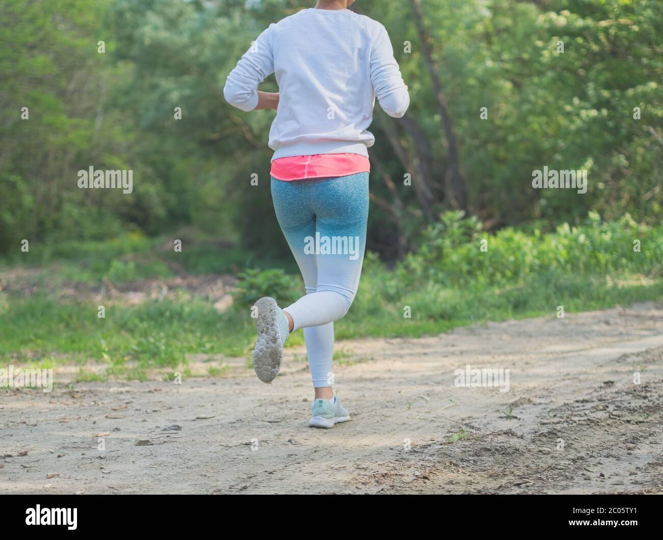 Junge kaukasische Frau läuft im Wald auf einer Feldstraße Nahaufnahme Stockfoto