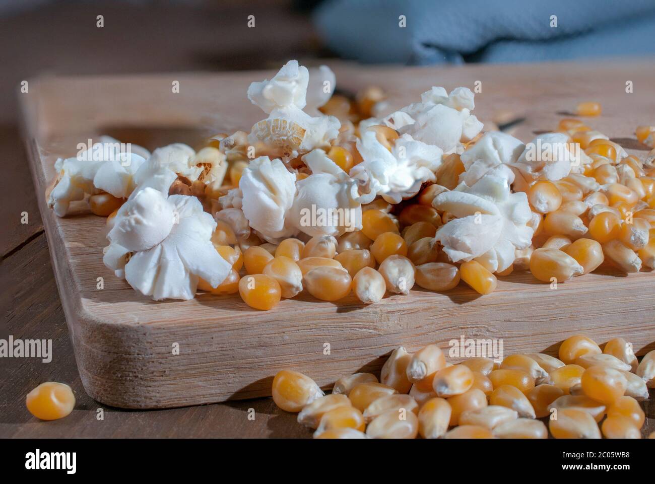 Getrockneter Mais und Popcorn auf einem Holzschneidebrett, Nahaufnahme oder Makrofotografie. Stockfoto