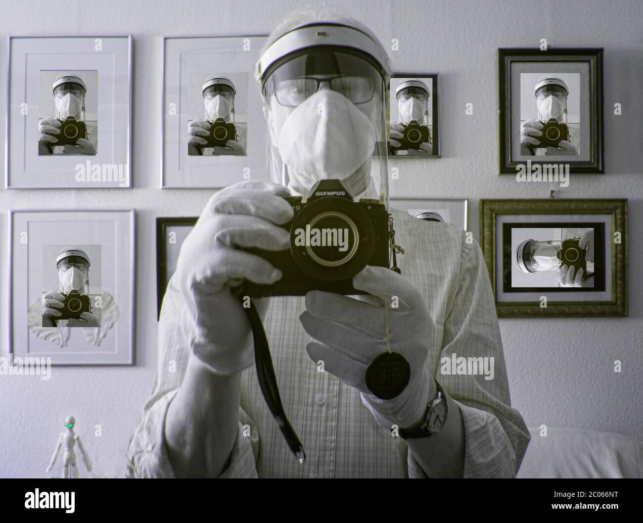 Mann fotografiert Selbstporträt mit Atemmaske, viele identische Porträts im Rücken Stockfoto