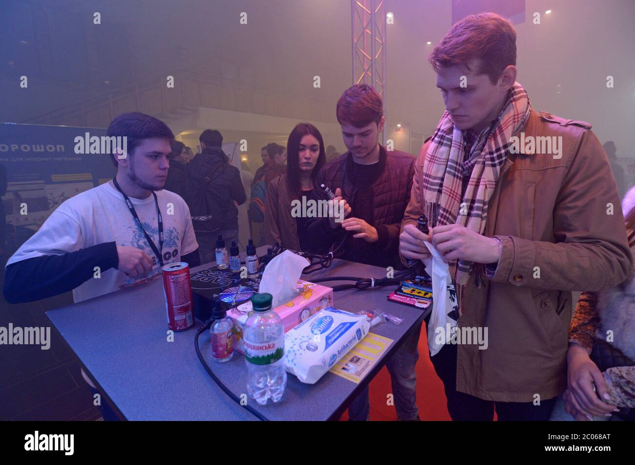 Verkäufer hinter einem Demo-Tisch zeigt Kunden, wie Vape Ladegerät funktioniert Stockfoto