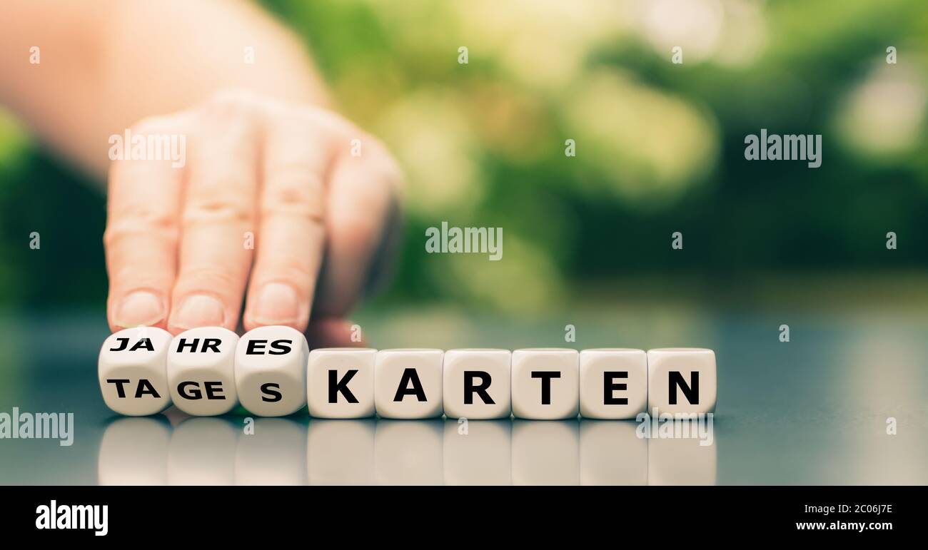 Hand dreht Würfel und ändert das deutsche Wort 'Tageskarten' in 'Jahreskarten'. Stockfoto