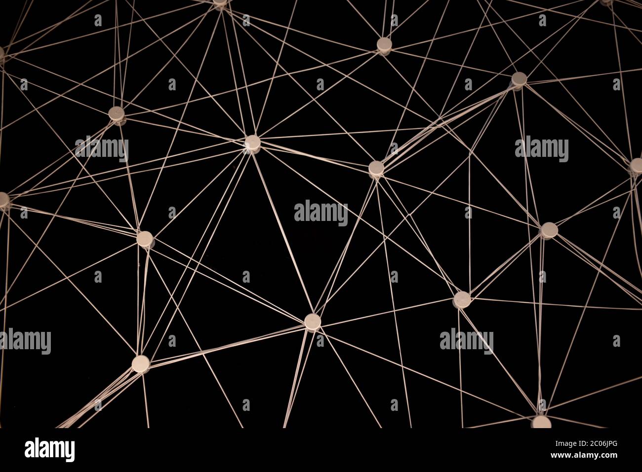 Ein komplexes Netz aus weißen Fäden, die zwischen beweglichen Punkten auf dunklem Hintergrund verflochten sind. Stockfoto