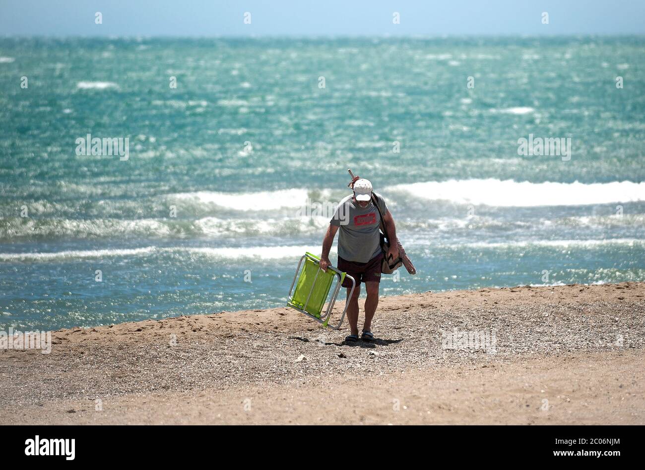 Ein Mann mit einem Klappstuhl verlässt den Strand während einer Warnung für  starke Winde am Strand Misericordia inmitten der Lockerung der  Beschränkungen für Phase 3 nach dem Plan der Abskalierung in Richtung