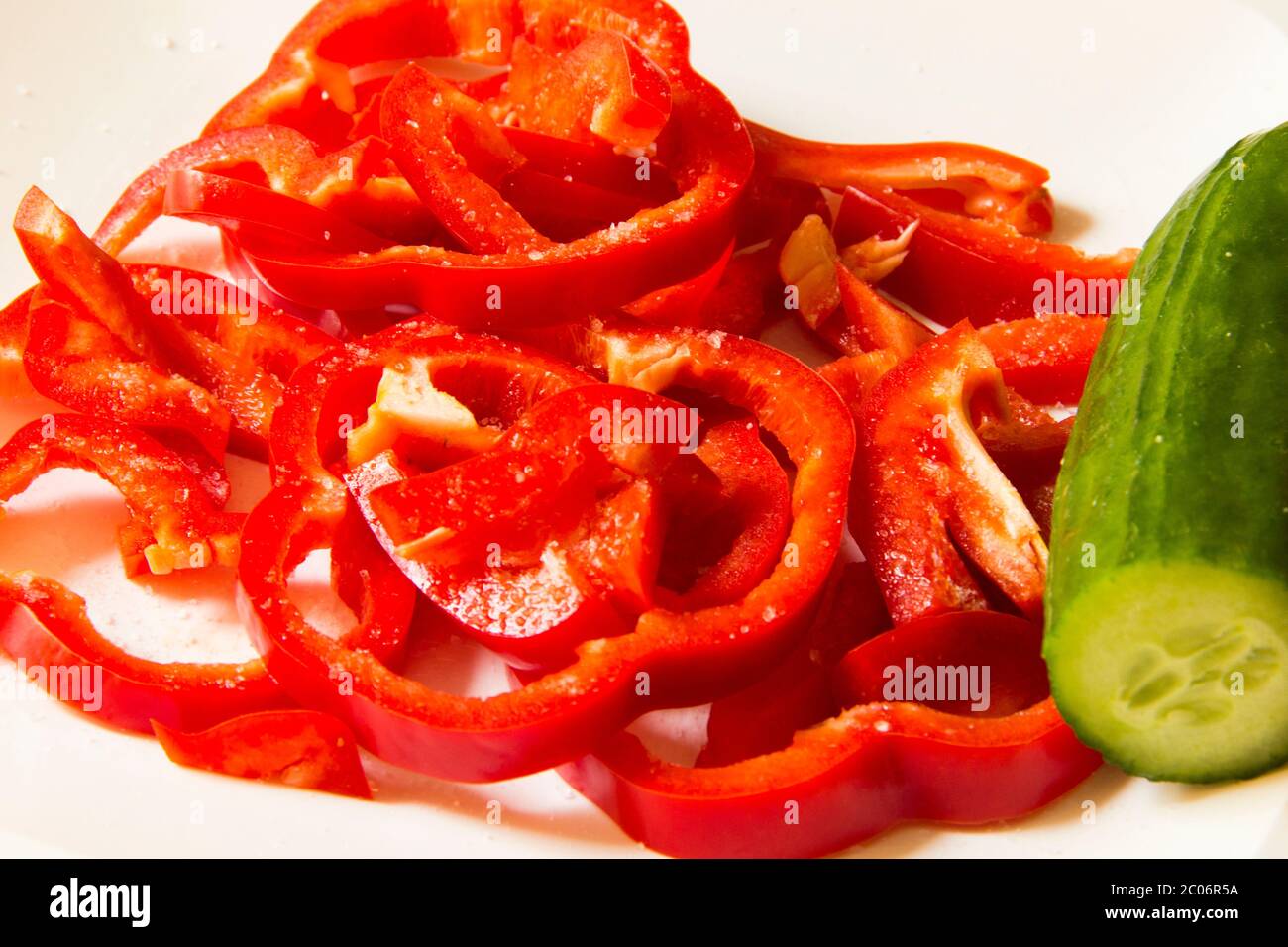Große geschnittene rote Paprika und Gurke auf weißem Hintergrund Stockfoto