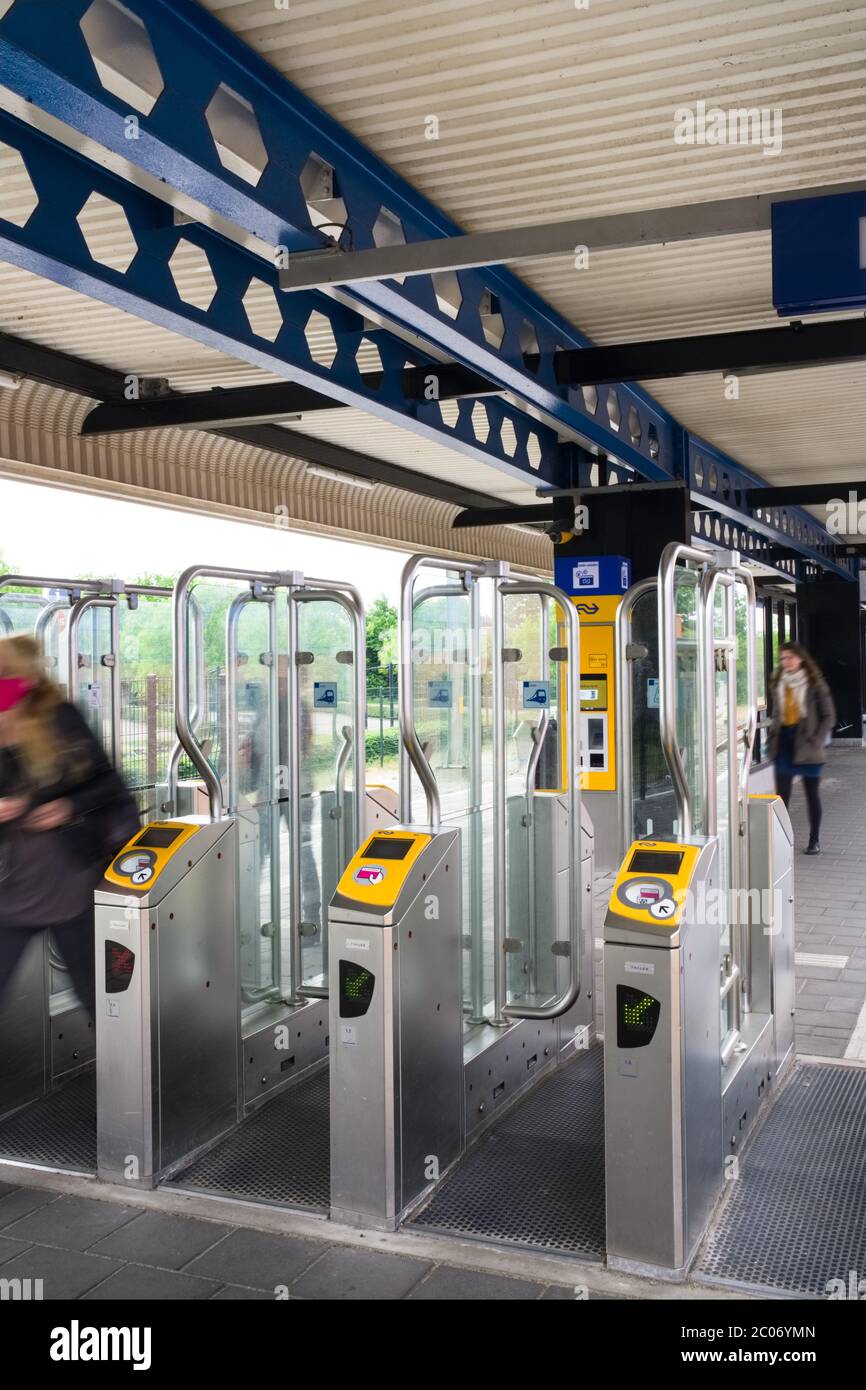Zwei Frauen mit Bewegungsunschärfe verlassen das automatische Check-in-Tor, um Zugang zum niederländischen Bahnhof Heerenveen zu erhalten Stockfoto