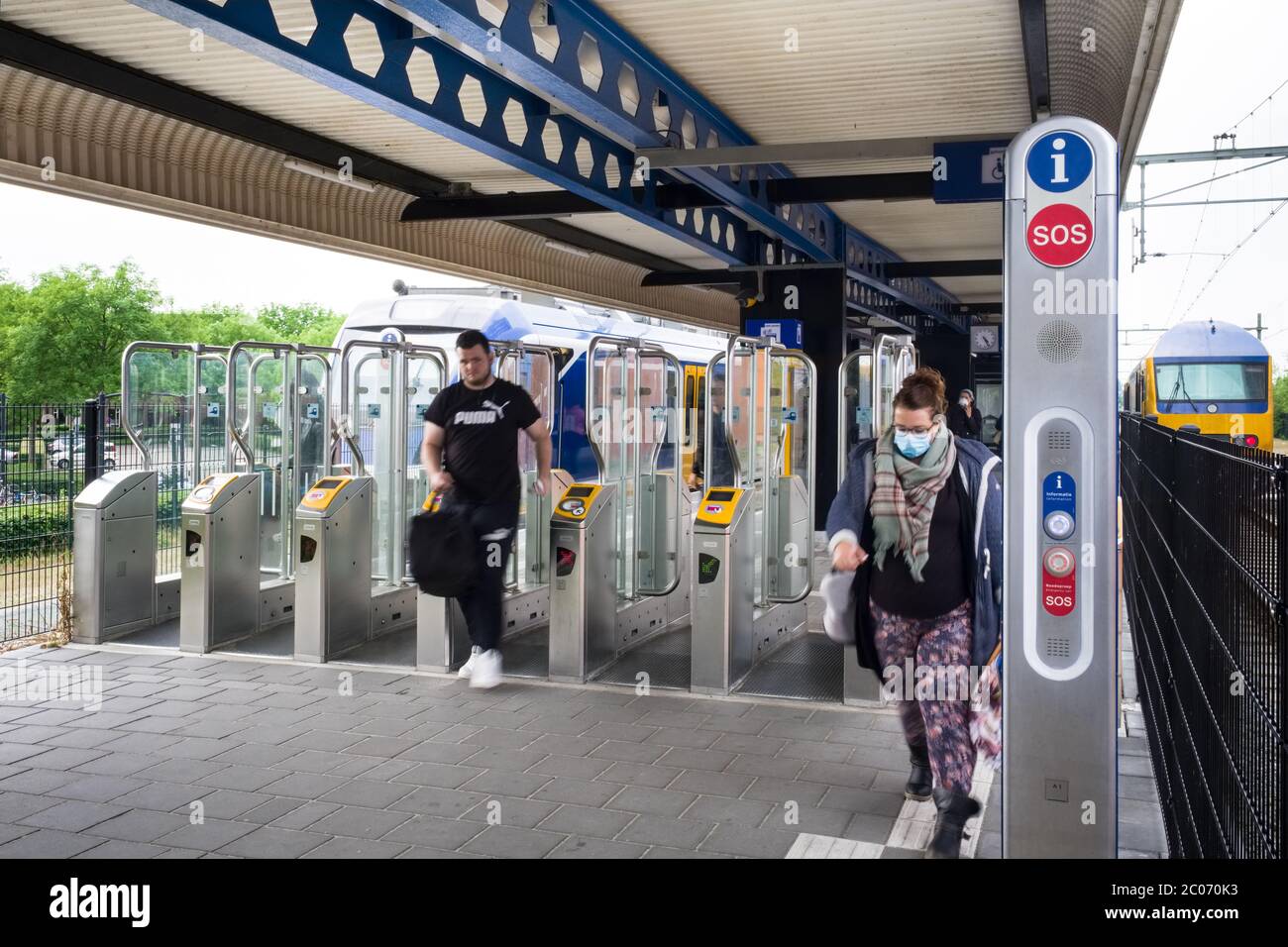 Frau mit Gesichtsmaske am automatischen Check-in-Tor am Bahnhof Heerenveen. Die Niederländer sind verpflichtet, Masken auf öffentlichen Transportwegen zu tragen Stockfoto