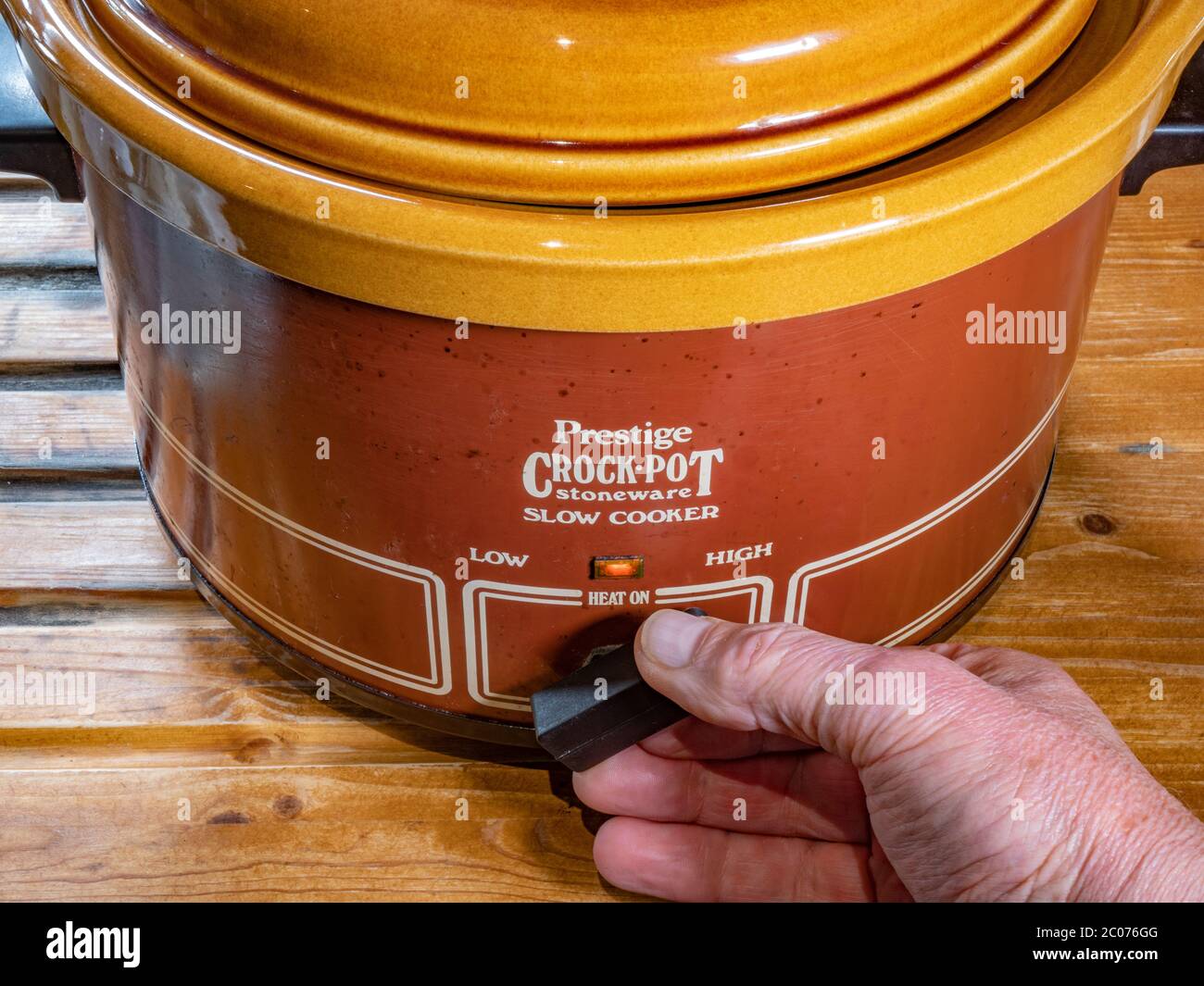 Handdrehung des Heizungsschalters an einem Vintage Prestige Steinzeug ‘Crock-pot’ - einem Steinzeug-Slow-Herd, hergestellt in den USA, beliebt in den frühen 1980er Jahren. Stockfoto