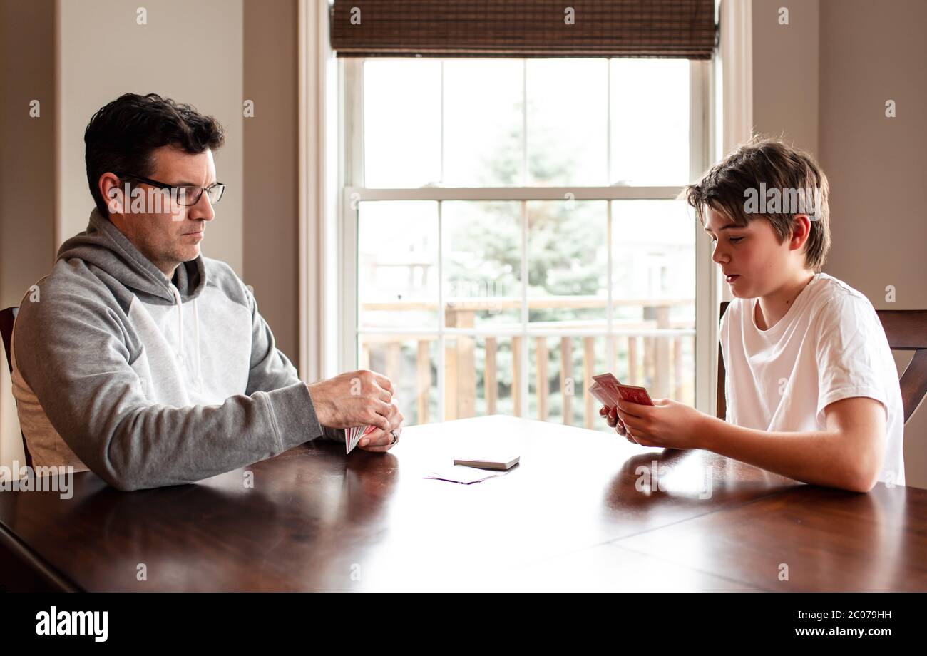 Der junge Mann und sein Vater spielen zusammen am Tisch Karten. Stockfoto