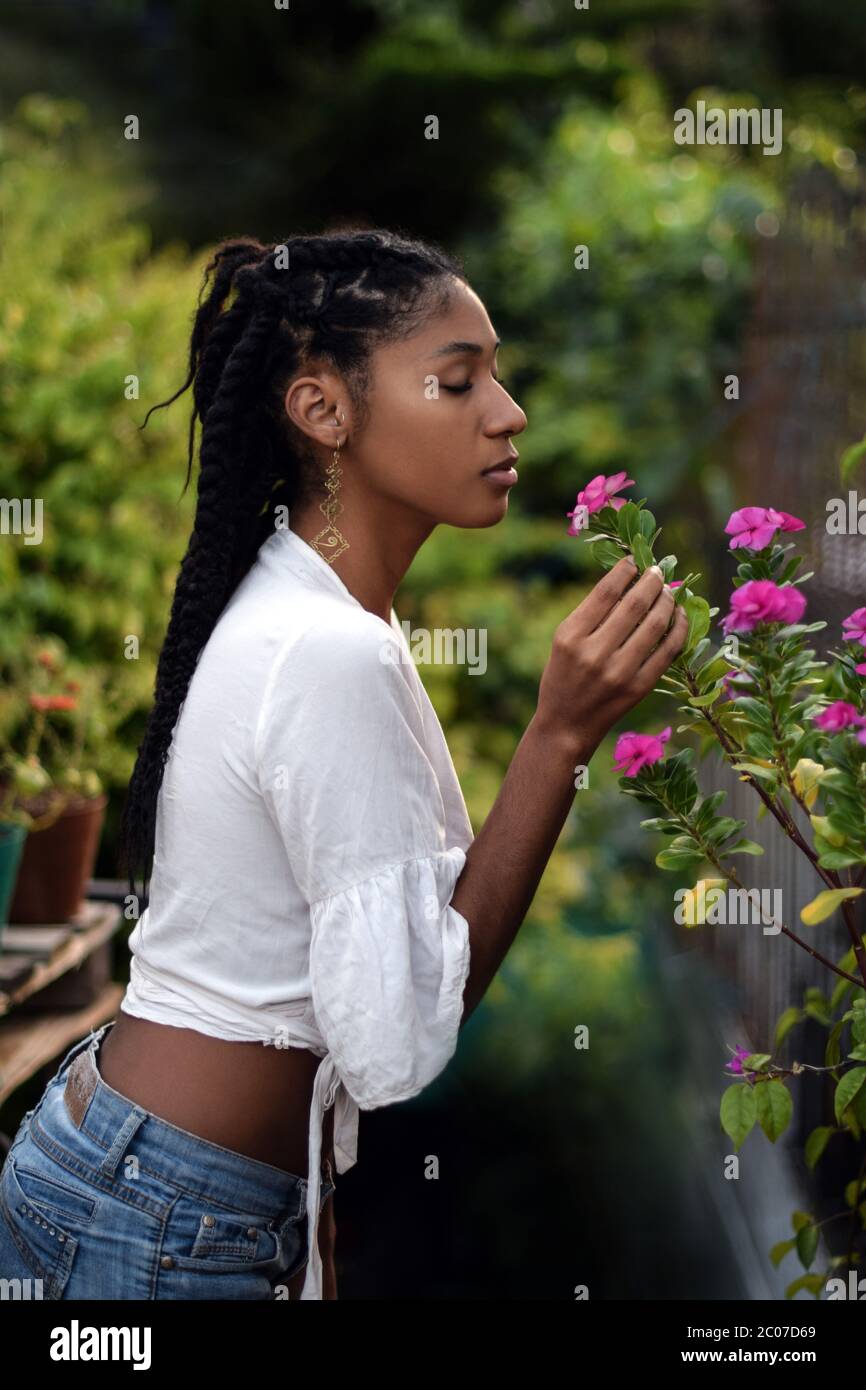 Junge schwarze Frau riecht Blumen Stockfoto