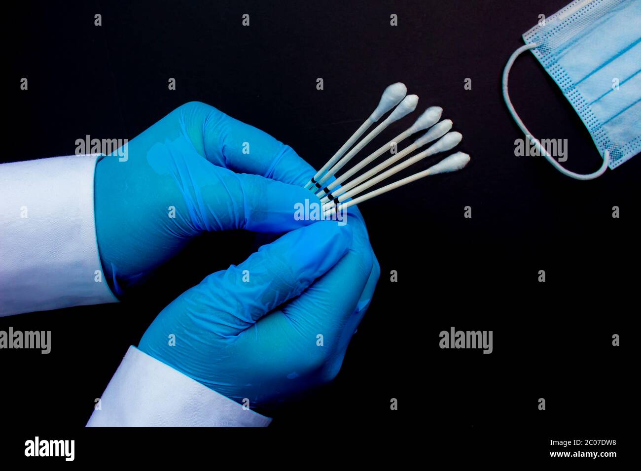 Ein medizinischer persönlicher Haltungskehlchen sticht neben einer medizinischen Gesichtsmaske auf schwarzem Hintergrund ab. Stockfoto