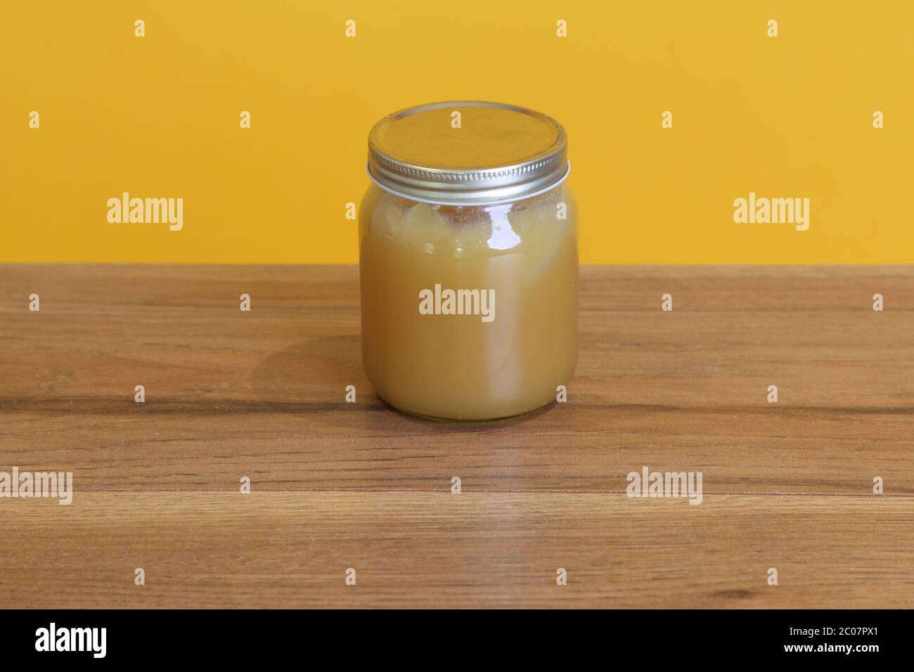 Ein Glas natürlichen creamed Honig unbeschriftet gegen gelb Stockfoto