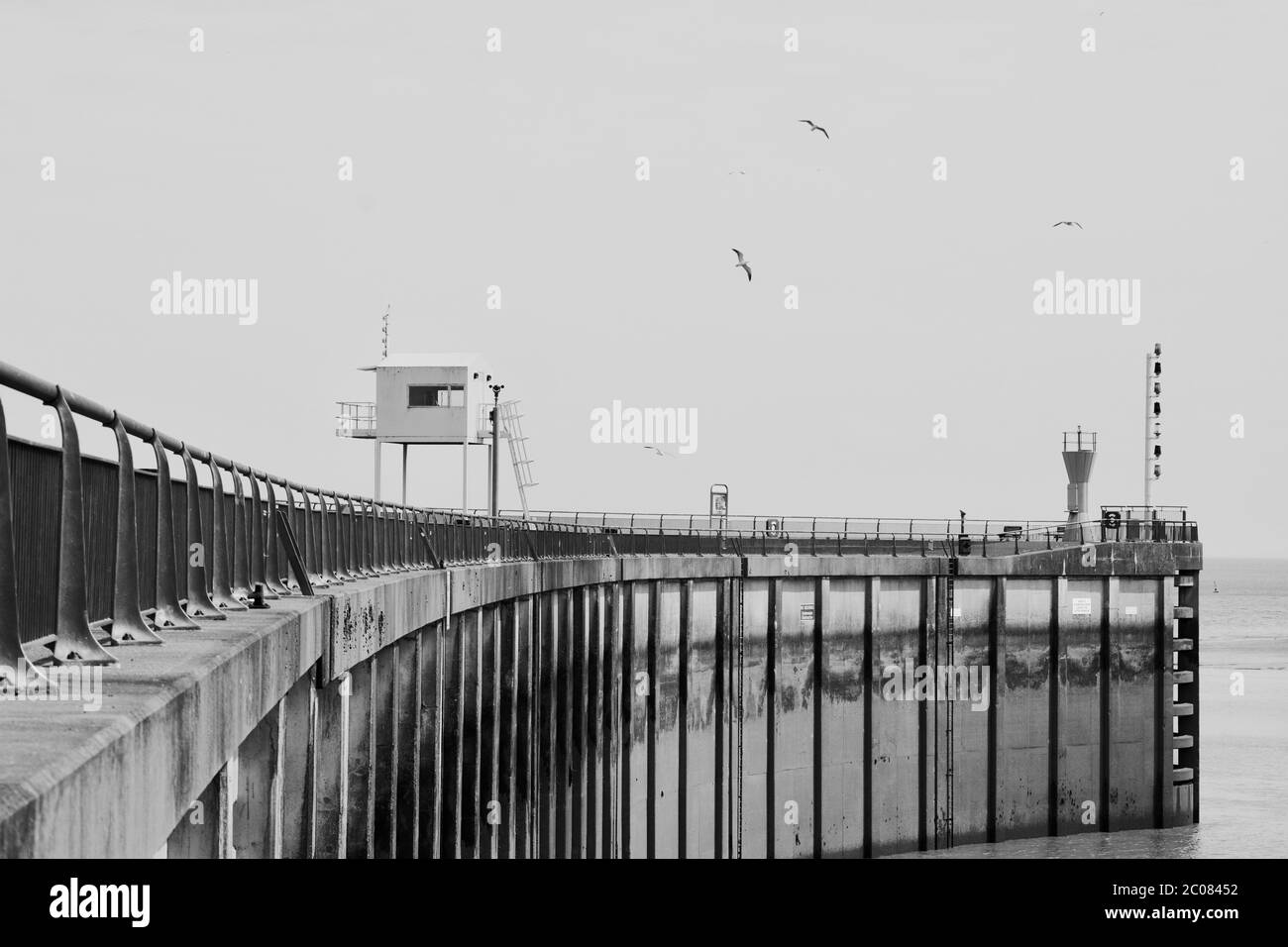 Fischer in Trawlern kommen mit ihrem Fang an Bord durch die Schleusentore der Cardiff Bay Barrage. Die Ebbe zeigt die Höhe der Strukturen Stockfoto