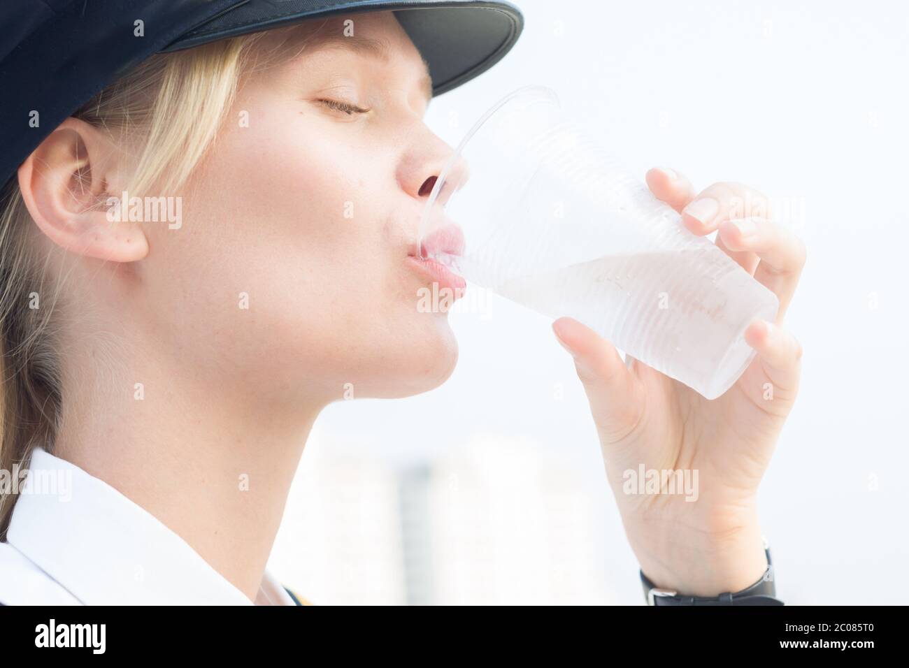 Eine aktive fraue Frau trinkt Wasser während ihrer Pause im Freien an einem sonnigen Tag. Stockfoto