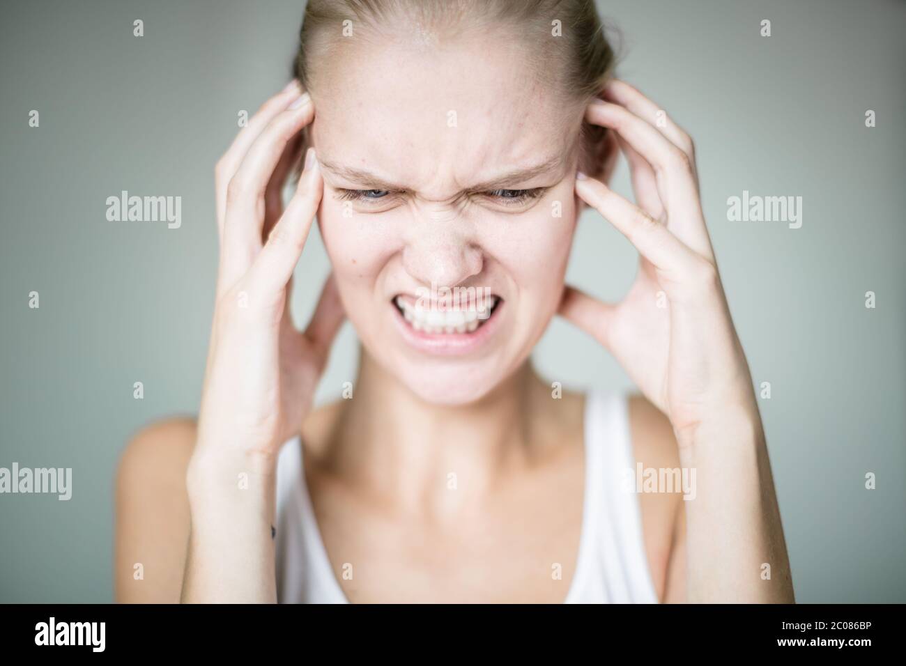 Eine verrückte Frau, die aus ihrer Umgebung verrückt wird und laute Geräusche hört, Hände auf ihrem Gesicht, die versuchen, ihren Kopf zu reinigen. Stockfoto
