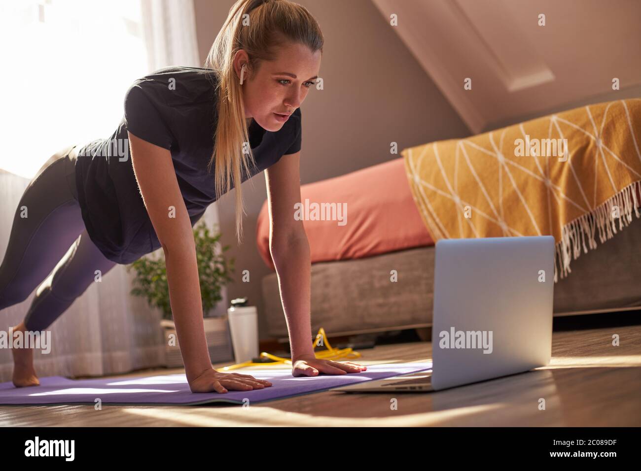 Junge Frau, die an Online-Fitness-Klasse vor dem Laptop. Stockfoto