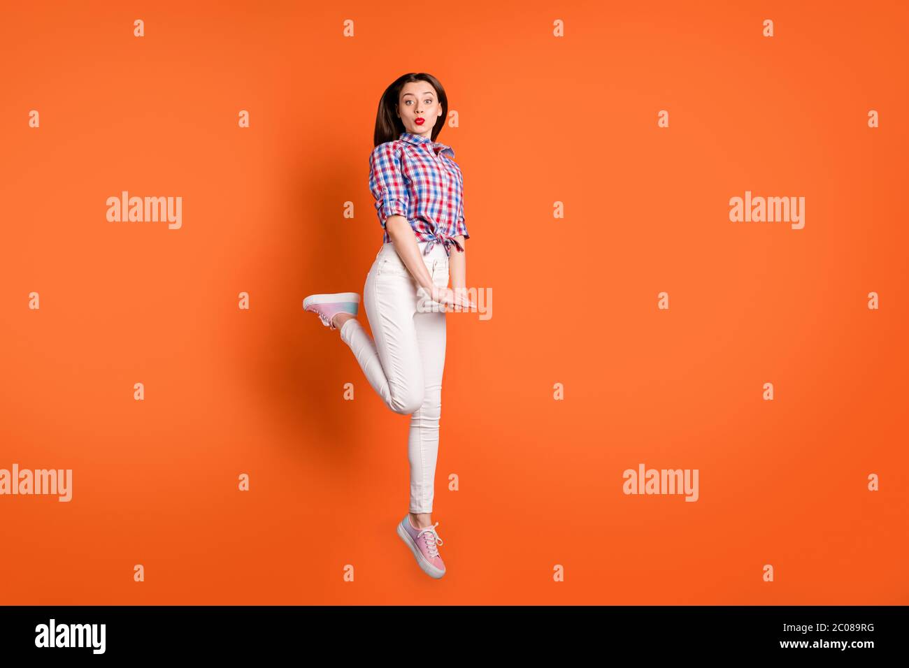 Foto in voller Größe von charmanten niedlichen Mädchen Liebhaber springen genießen Ruhe entspannen senden Luft Küsse tragen gut aussehende Kleidung isoliert über orange Farbe Hintergrund Stockfoto