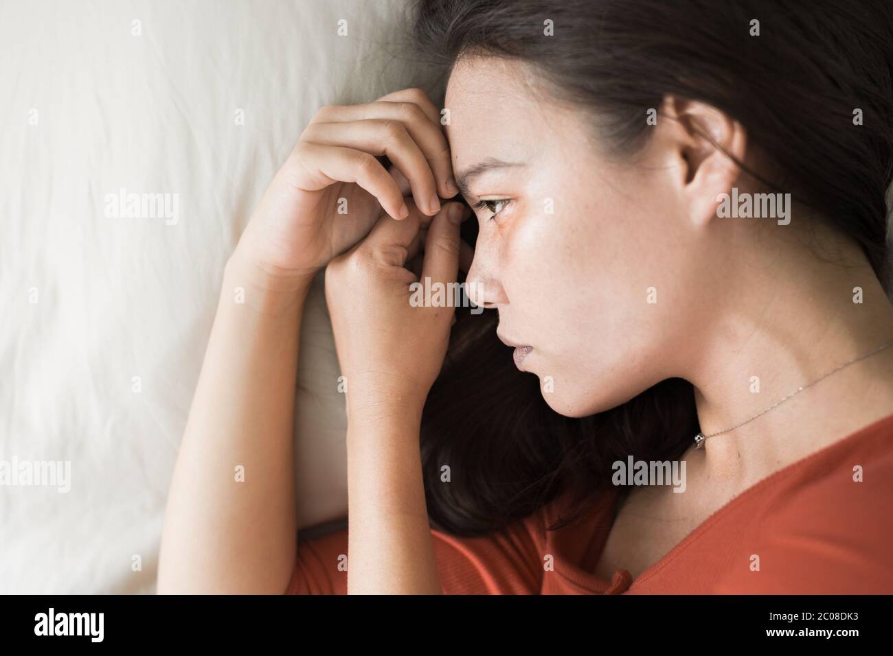Eine Frau, die unter tiefer Depression leidet, über ihre Probleme nachdenkt, auf dem sie liegt Stockfoto