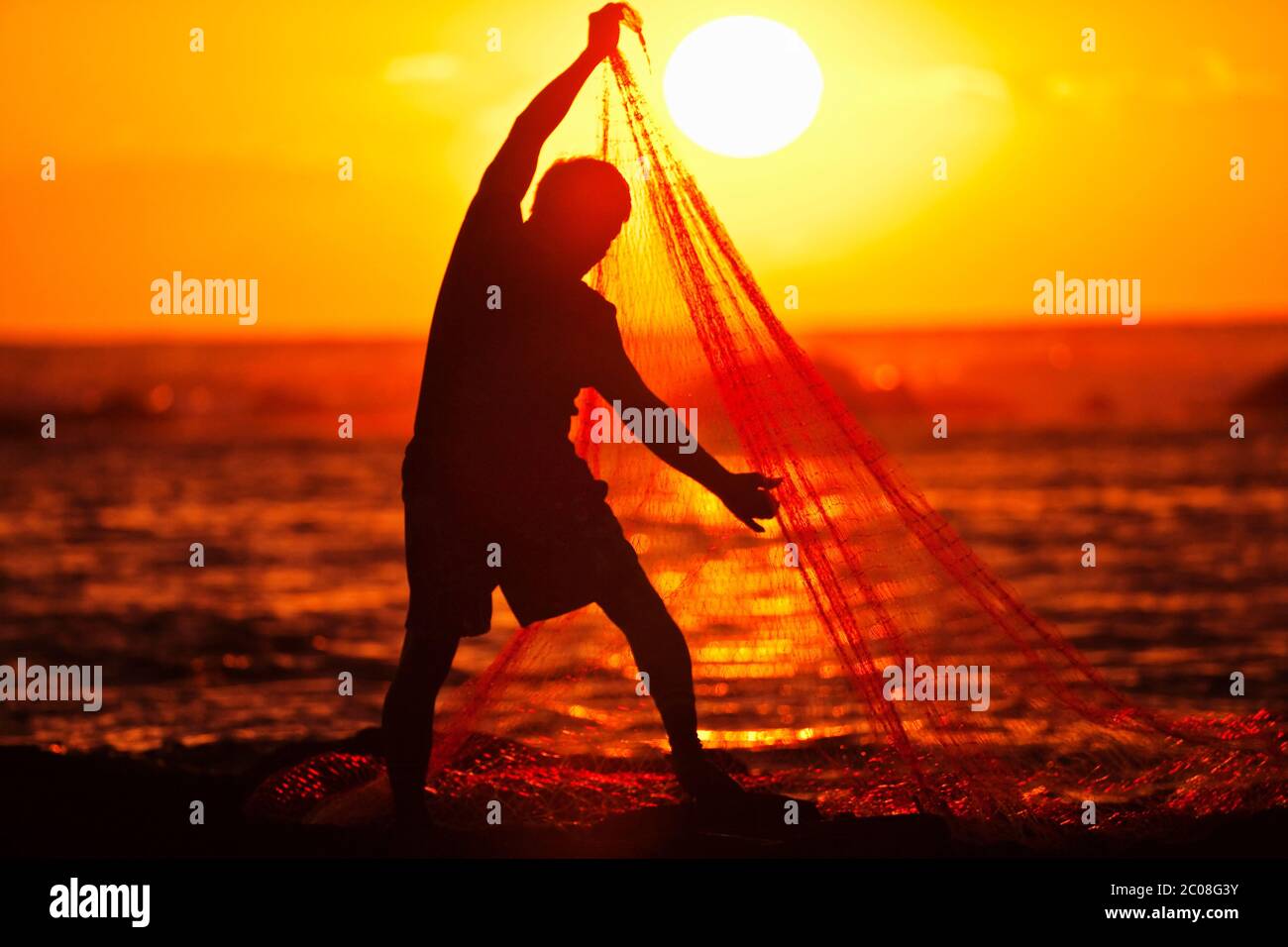 Hawaiian Fisherman (Model released) schleppt in seinem Fischernetz bei Sonnenuntergang in Keauhou, Hawaii Stockfoto