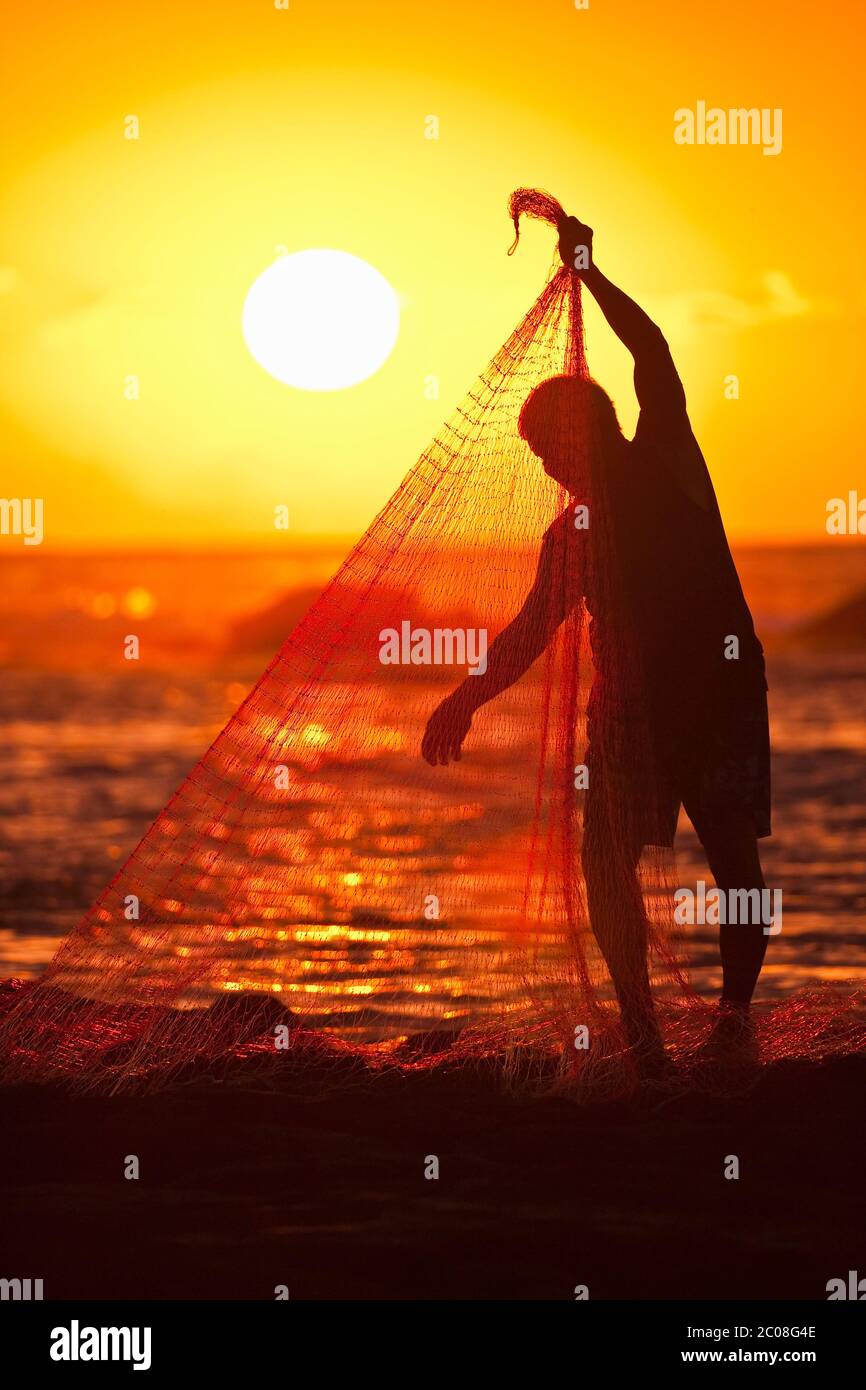 Hawaiian Fisherman (Model released) schleppt in seinem Fischernetz bei Sonnenuntergang in Keauhou, Hawaii Stockfoto