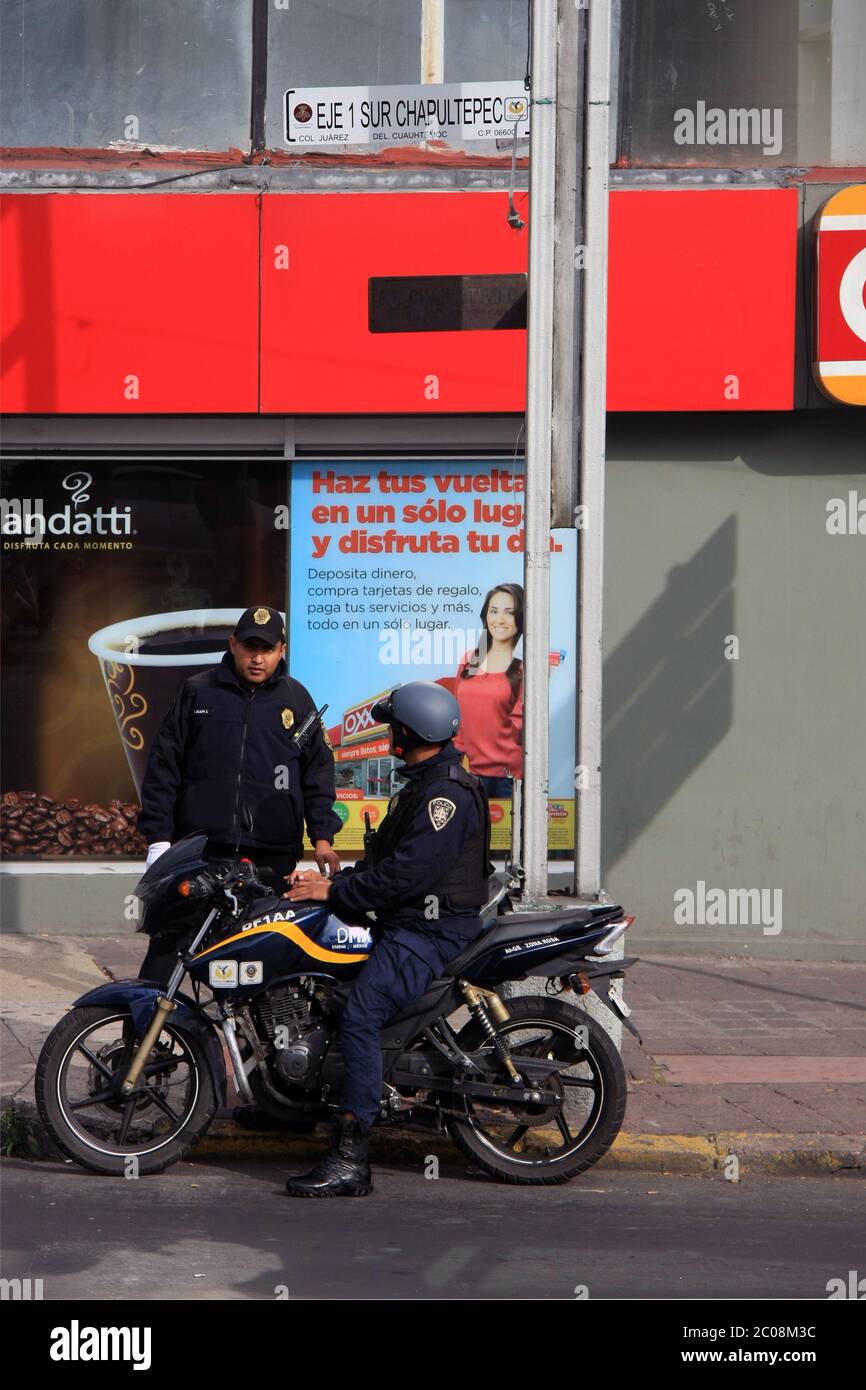 Mexiko-Stadt, Mexiko - 27. November 2015: Zwei mexikanische Polizeibeamte [Bundespolizei], einer auf einem Motorrad, der vor einem Geschäft mit dem anderen sprach Stockfoto