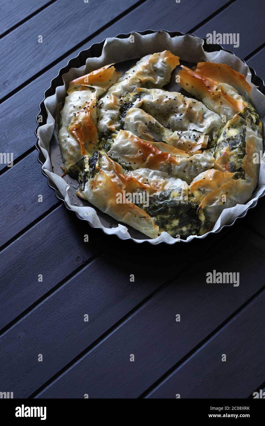 Konzept der griechischen Küche. Gerollte Spanakopita, griechischer Phylo-Gebäck Pie mit Spinat und Feta-Käse auf dunklem Licht. Draufsicht, Kopierbereich. Stockfoto