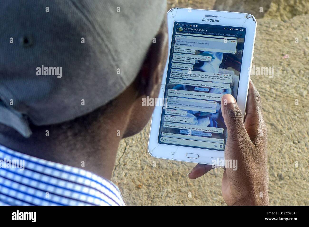 Breggnave Sikahika, Autor von Büchern, die nur über soziale Medien erhältlich sind, betrachtet Nachrichten einer WhatsApp-Gruppe von Fans seiner Arbeit. Da jedes Jahr mehr Simbabwer das Internet und Smartphones nutzen, können Leser auf neue Weise auf Literatur zugreifen. (Sharon Munjenjema, GPJ Simbabwe) Stockfoto