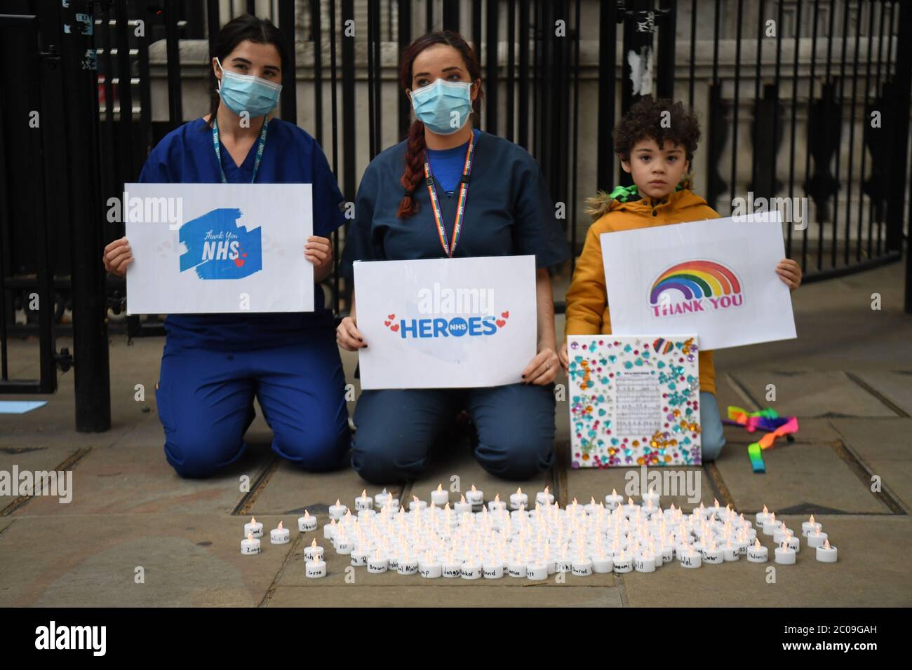 Krankenschwestern sitzen mit brennenden Kerzen mit den Namen von 235 Gesundheits- und Sozialarbeitern, die während einer Mahnwache vor Downing Street, London, an Coronavirus gestorben sind. Stockfoto