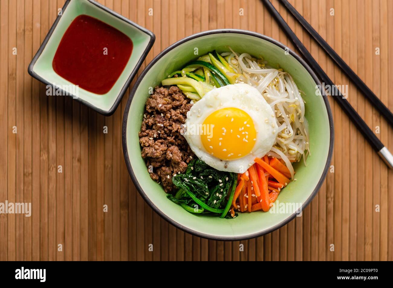 Blick von oben auf Bibimbap, ein klassisches koreanisches Essen. Reis wird mit gewürztem Gemüse, Fleisch und einem sonnigen Seite up Spiegelei auf der Oberseite gekrönt. Stockfoto Blick von oben auf Bibimbap, ein klassisches koreanisches Essen. Reis wird mit gewürztem Gemüse, Fleisch und einem sonnigen Seite up Spiegelei auf der Oberseite gekrönt. Stockfoto