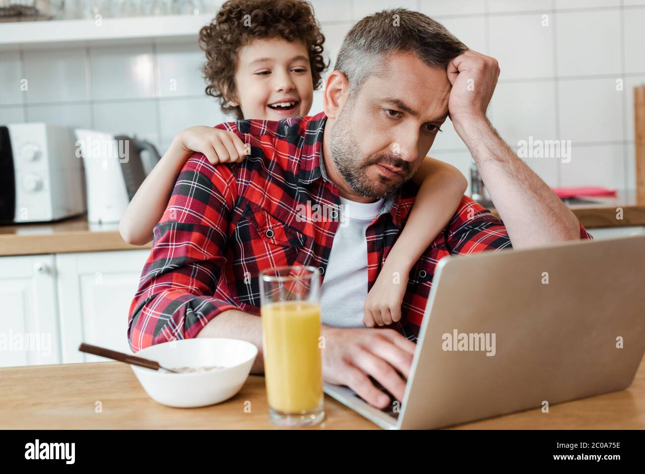 Selektiver Fokus des glücklichen Sohnes berühren müde Freelancer Vater von zu Hause aus Stockfoto