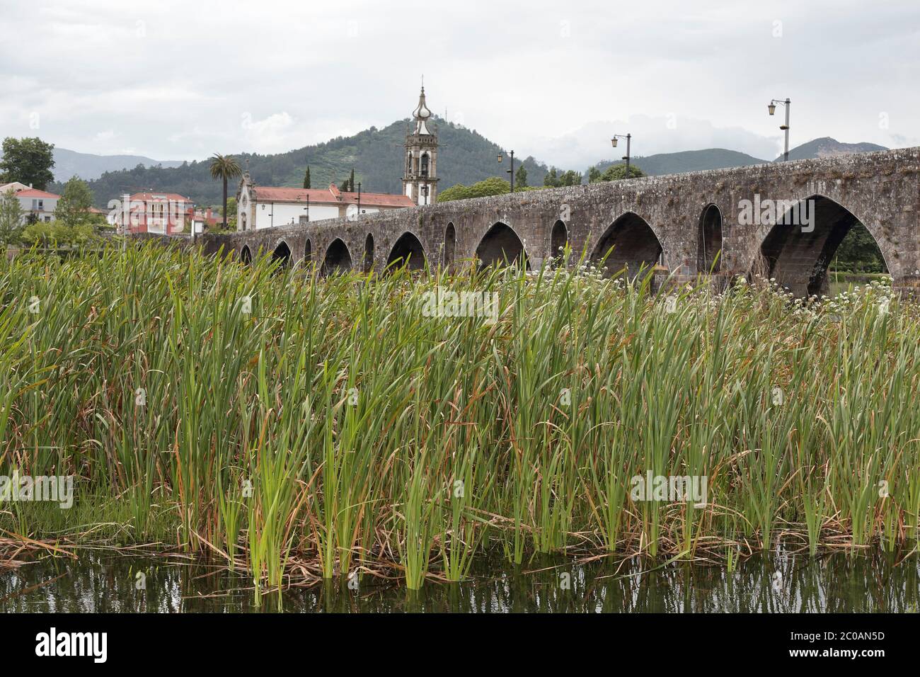 Alte Granitbrücke und Kirche aus der mittelalterlichen Stadt Ponte de Lima an einem regnerischen Tag. nordportugiesischer Weg nach Santiago de Compostela. Stockfoto