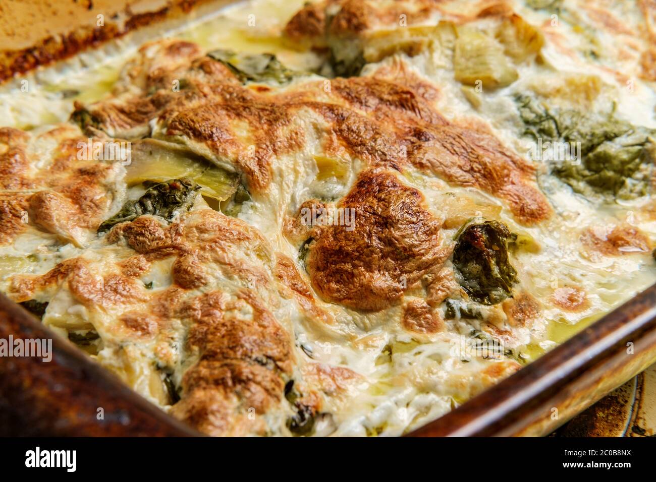 Auflaufform mit Hühnchen und Artischocken, knusprig mit Mozzarella und Spinat Stockfoto