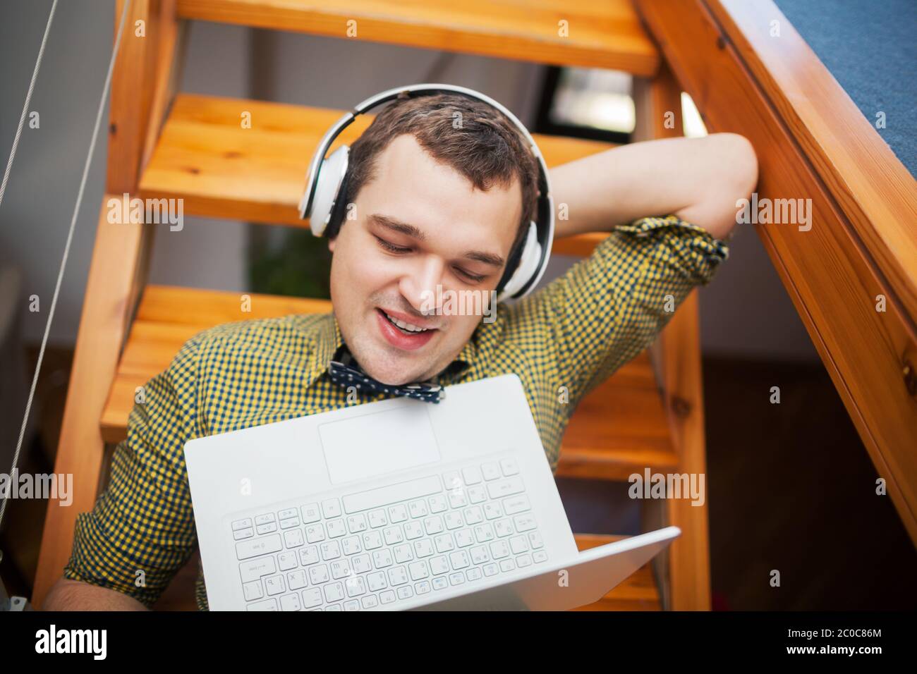 Mann mit Laptop und Musik zu Hause unterhaltsam Stockfoto