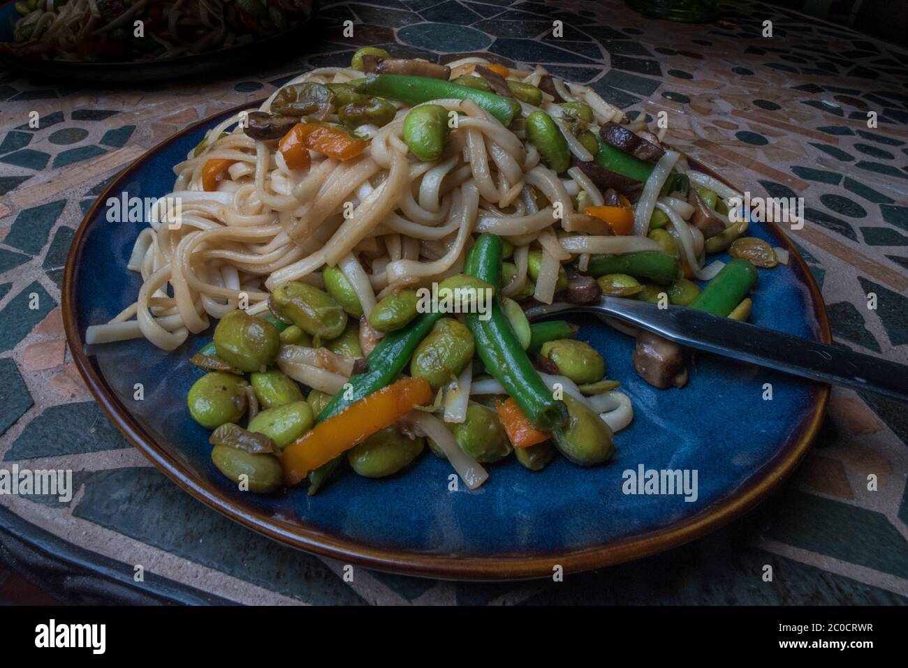 Ein veganes Nudelgericht mit Gemüse wie Karotten, grünen Bohnen und Edamame. Stockfoto