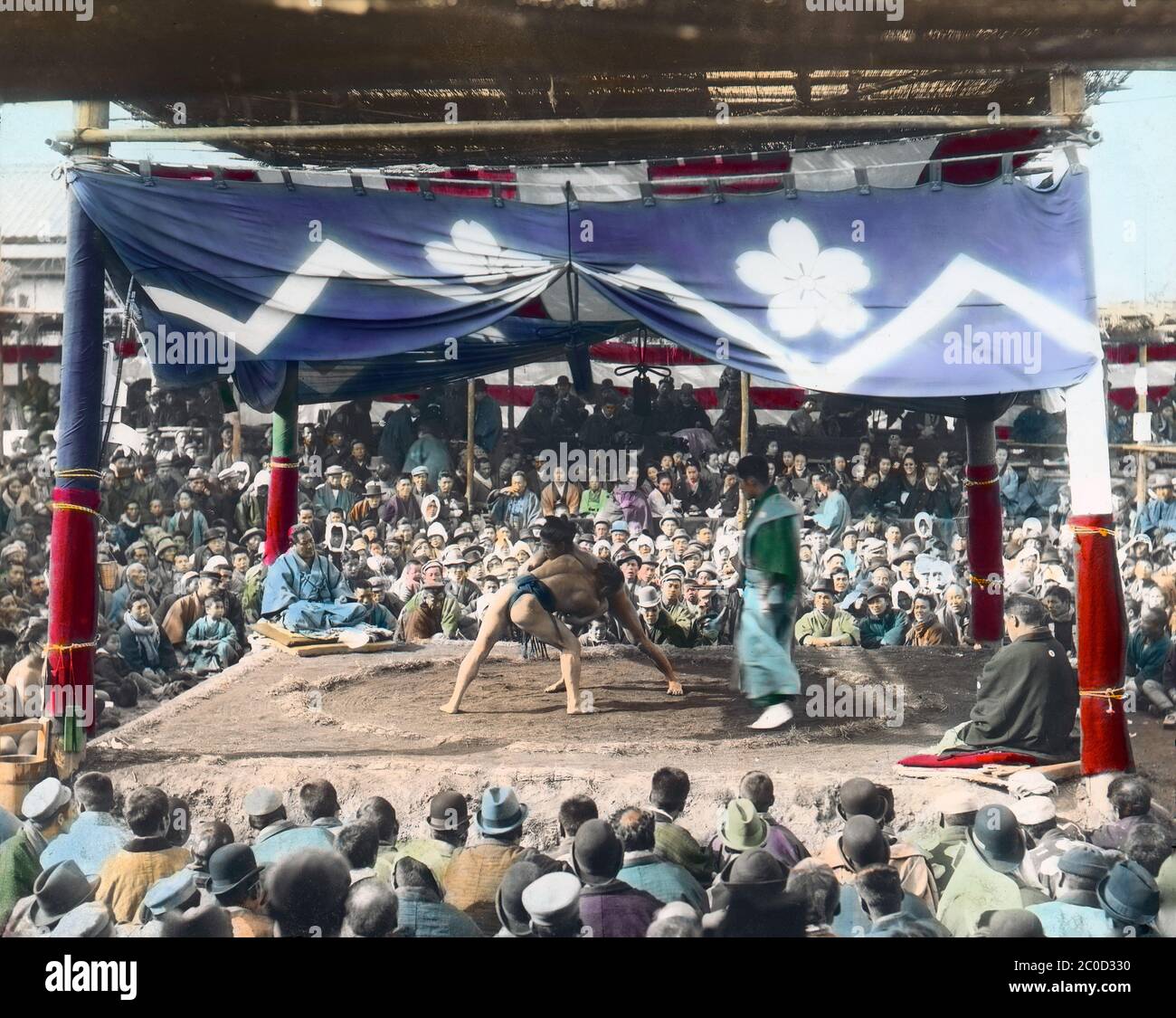 [ 1900er Japan - Japanischer Sumo Wrestling ] - Sumo-Ringer in einer Außenarena im Eko-in Tempel (回向院) in Ryogoku, Tokyo in der Mitte eines Kampfs. Der Tempel war als Sumo-Wrestling-Veranstaltungsort während der Edo (1603-1868) und Meiji (1868-1912) Perioden bekannt. Der erste Kampf fand hier im September 1768 statt. Vom 1833. Oktober (Tenpo 4) bis 1909 (Meiji 42), der Zeit des „Eko-in Sumo“ (回向院相撲), fanden alle Sumo-Turniere im Tempel statt. Vintage-Glasrutsche aus dem 20. Jahrhundert. Stockfoto