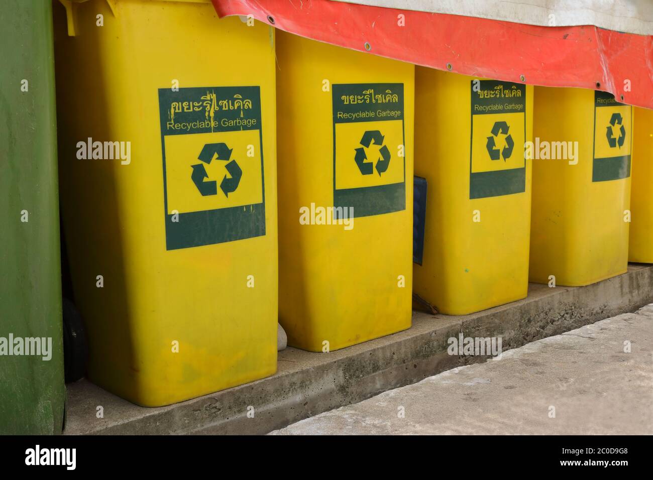 Nahaufnahme und selektiver Fokus der Reihe von Mülltonnen mit recyclebaren Müll Zeichen in englisch und thai, auf Zementboden in der Nähe Müllraum stehen Stockfoto