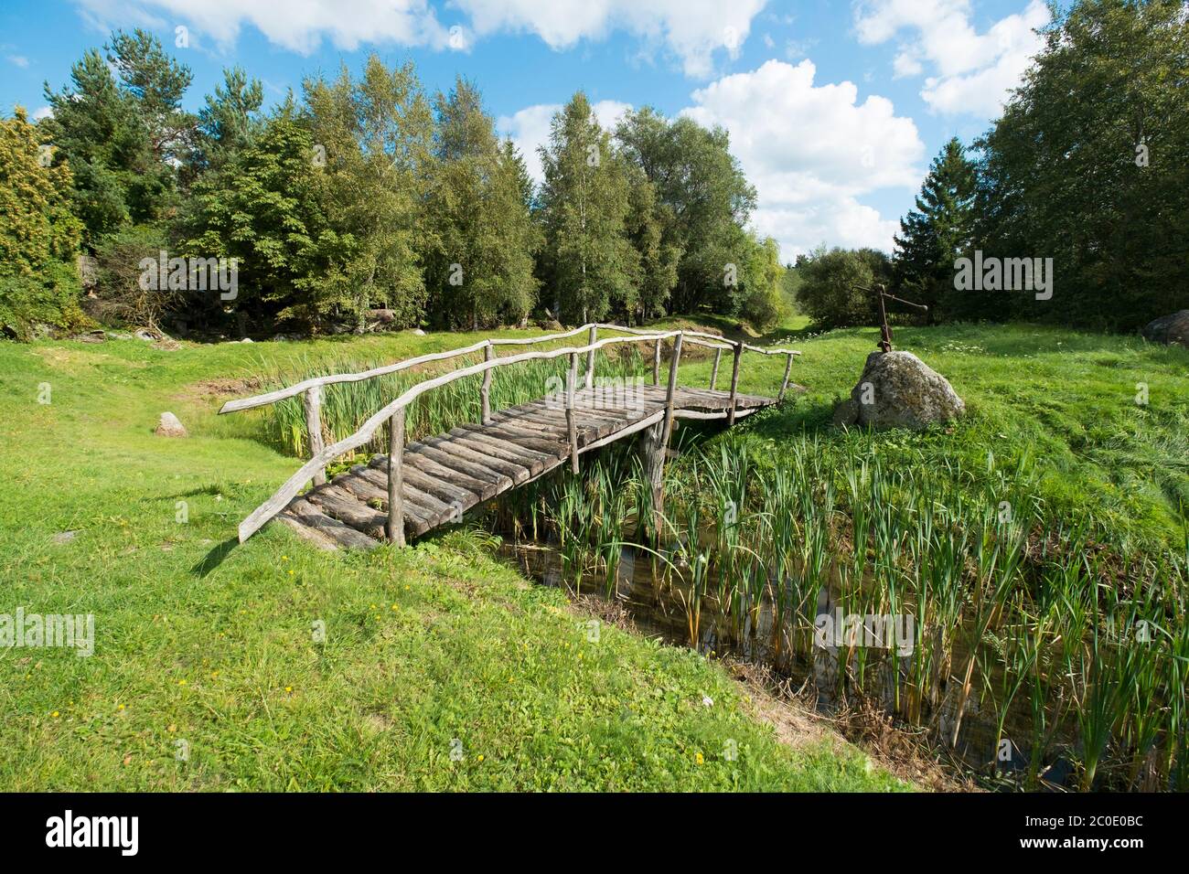 Eine schöne, klassische, alte Holzbrücke über einen kleinen Bach. Im neugierigen, hausgemachten Orvydas Garten in Salantai, Litauen. Stockfoto