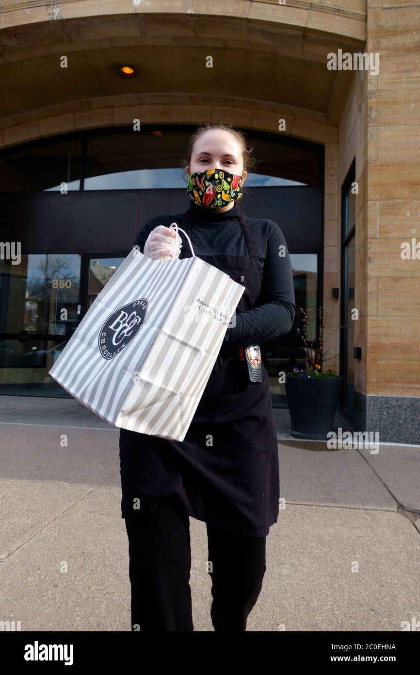 Lieferperson aus Cafe Latte, die mit Handschuhen und Maske Essen zum Auto bringt und dabei soziale Distanzierung beobachtet. St. Paul Minnesota, USA Stockfoto