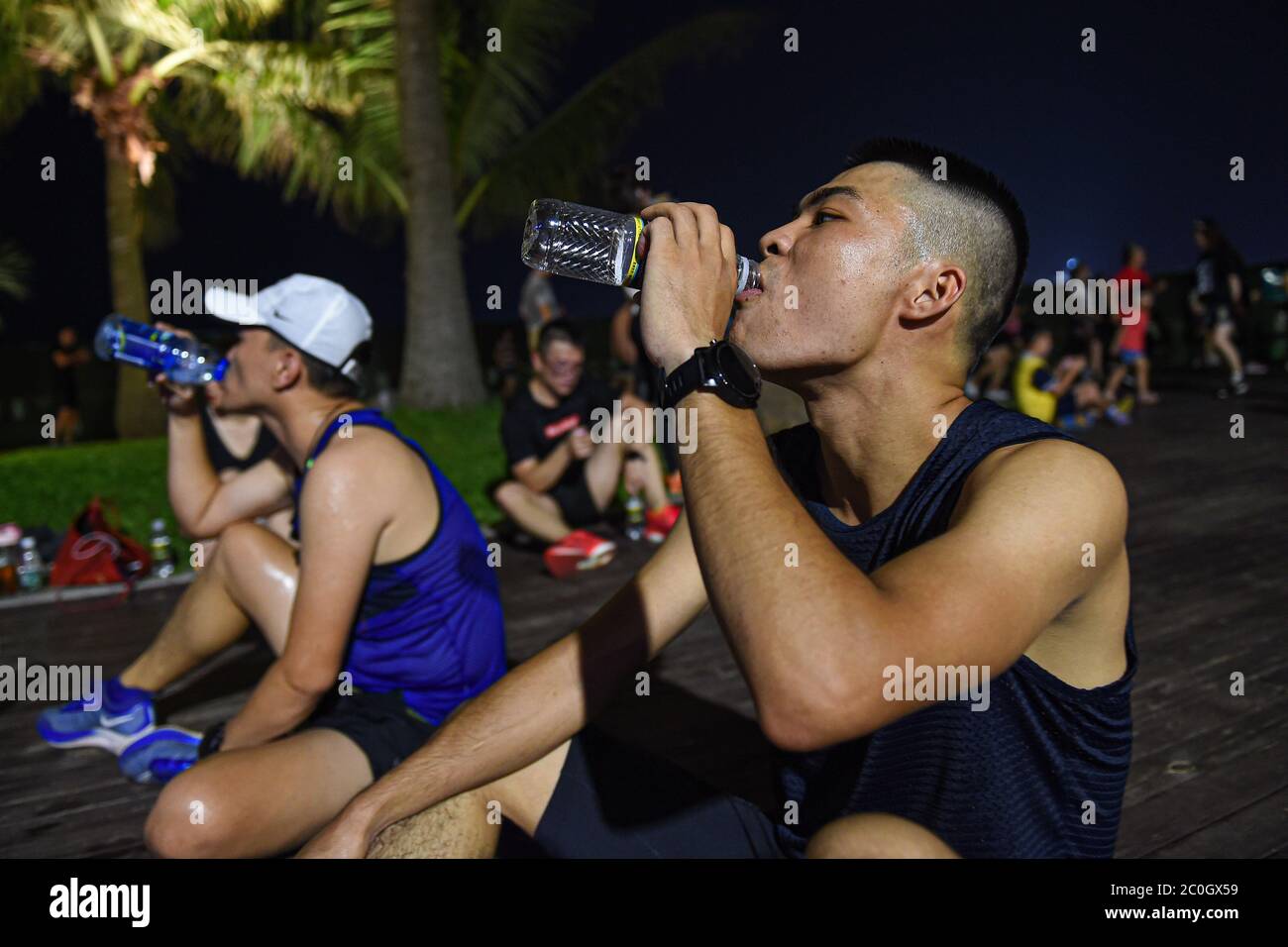 Haikou, Chinas Provinz Hainan. Mai 2020. Chen Junru (R) trinkt nach einem Nachtlauf im Wanlu Park in Haikou, südchinesische Provinz Hainan, 21. Mai 2020. Night Run ist ein beliebter Sport unter den Bürgern in Haikou geworden. Quelle: Pu Xiaoxu/Xinhua/Alamy Live News Stockfoto