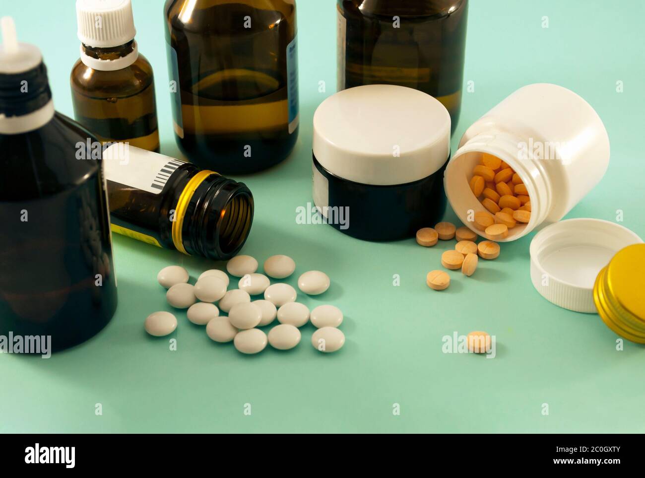 Orange und weiße Pillen, Pillen und Lösung auf blauem Hintergrund. Pillen mit weißen und orangefarbenen, Glasgefäße auf blauem Hintergrund verstreut. Stockfoto