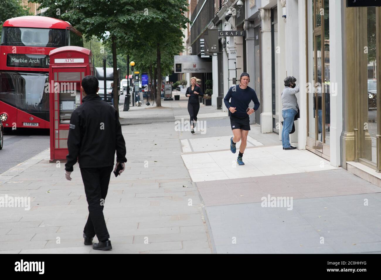 Besucher von Knightsbridge im Westen Londons gehen durch die leeren Straßen, während sich die Geschäfte darauf vorbereiten, ihre Türen am Montag, den 15. Juni, nach der Einführung von Maßnahmen zur Lockerung Englands zu öffnen. Händler bereiten sich auf die Wiedereröffnung von Geschäften vor, die erst seit Beginn der Sperrung im März online handeln dürfen. Stockfoto