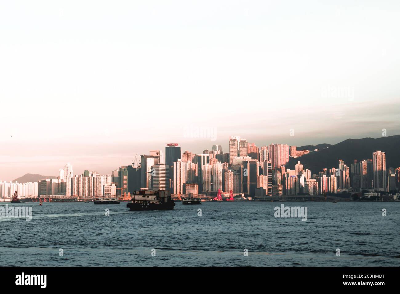 Frachtschiffe überqueren den Victoria Harbour in Hongkong China bei Sonnenuntergang Stockfoto