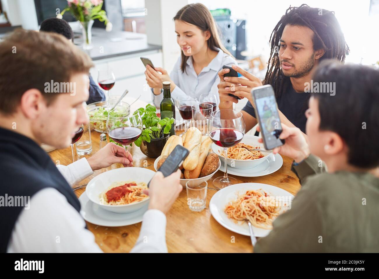 Gruppenleute, die am Tisch zusammen essen, betrachten den Smartphone-Bildschirm Stockfoto