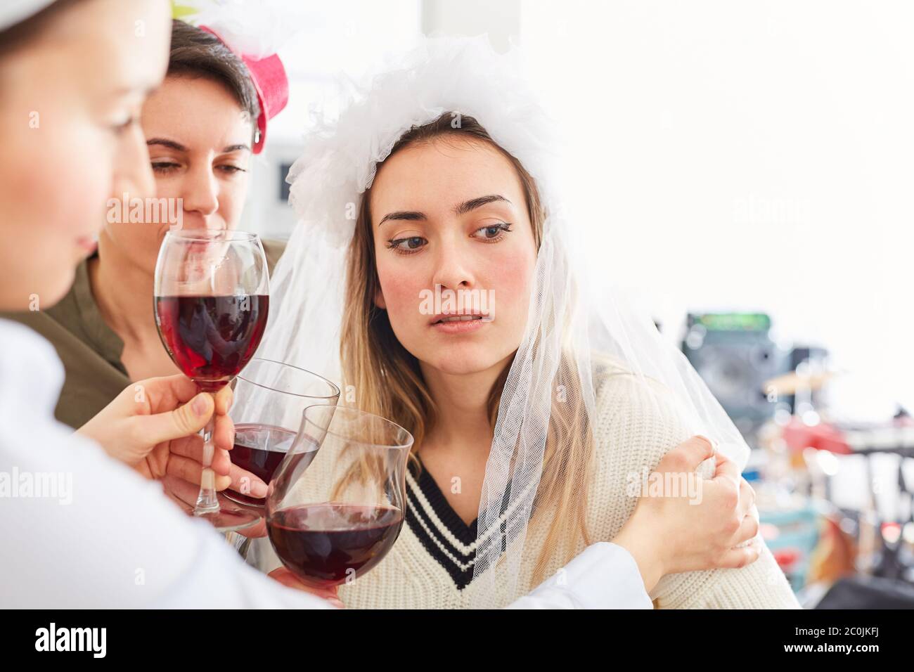 Freunde trösten traurig und enttäuscht Braut mit einem Glas Rotwein auf Junggesellenabschied Stockfoto
