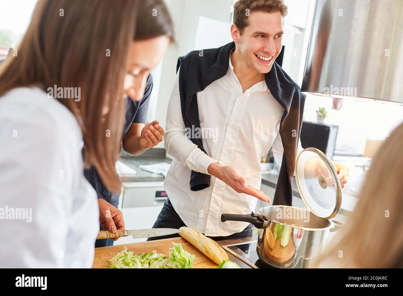 Lachende Studenten bereiten gemeinsam Mahlzeiten in einer Gemeinschaftsküche zu Stockfoto